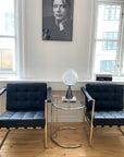 Moderne stol i sort læder med slankt stålstel og armlæn